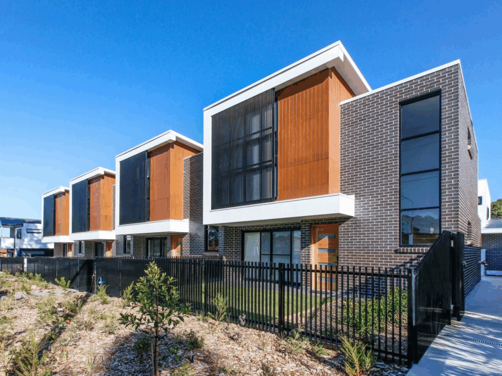 A row of modern townhomes with brick, wood panels, and large windows