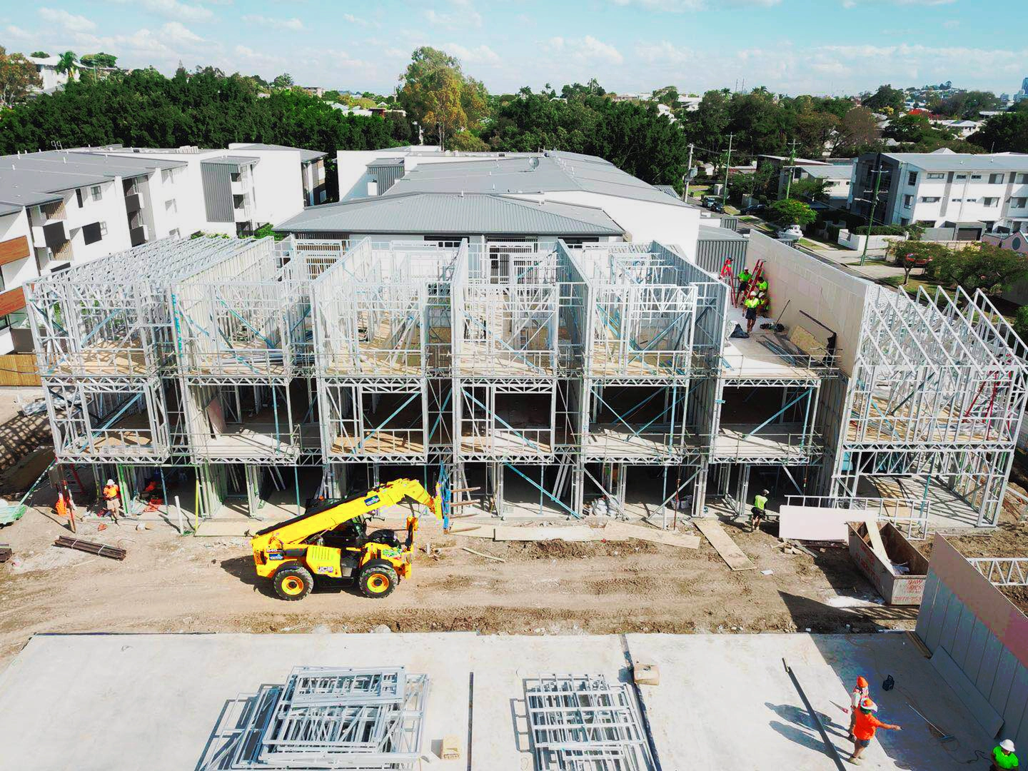 A large building site showing several units framed with light steel and workers on the ground