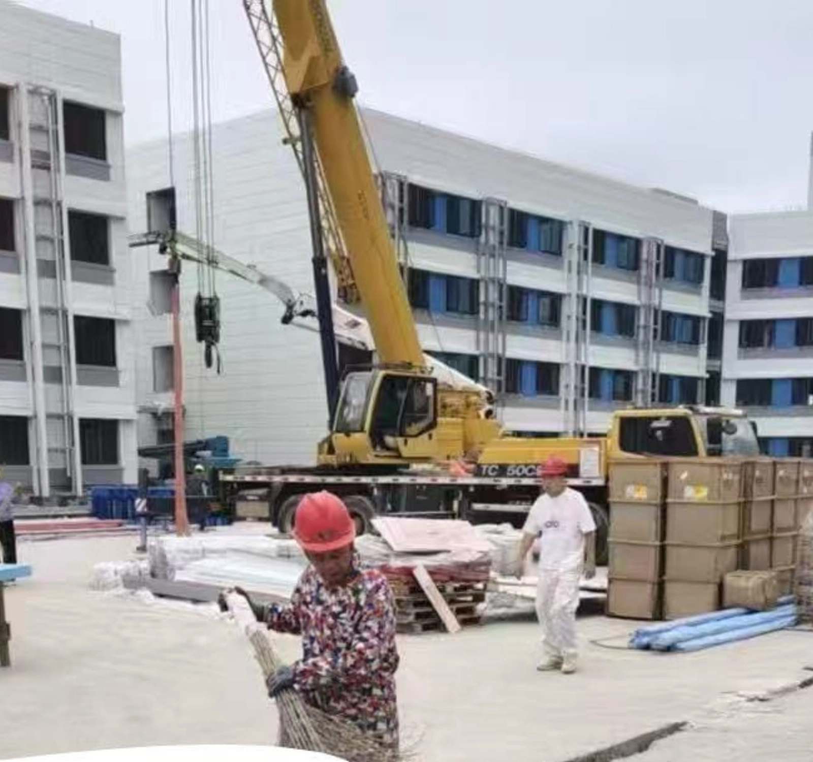 Construction workers guiding a crane while building a multi-story student housing complex.